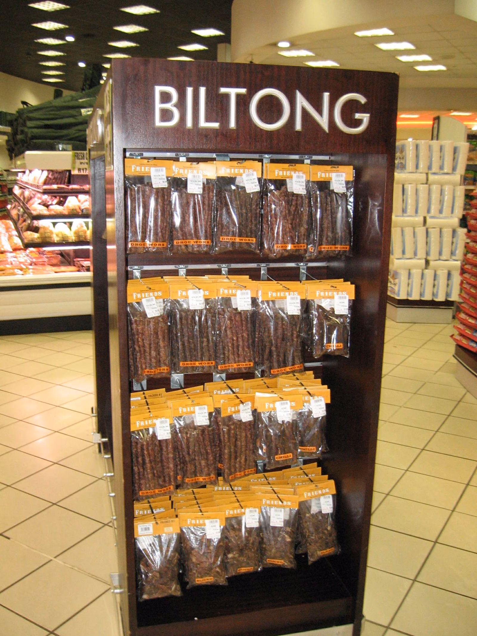 Racks of packaged dried meat strips hanging in a supermarket aisle, each pack labelled and priced.
