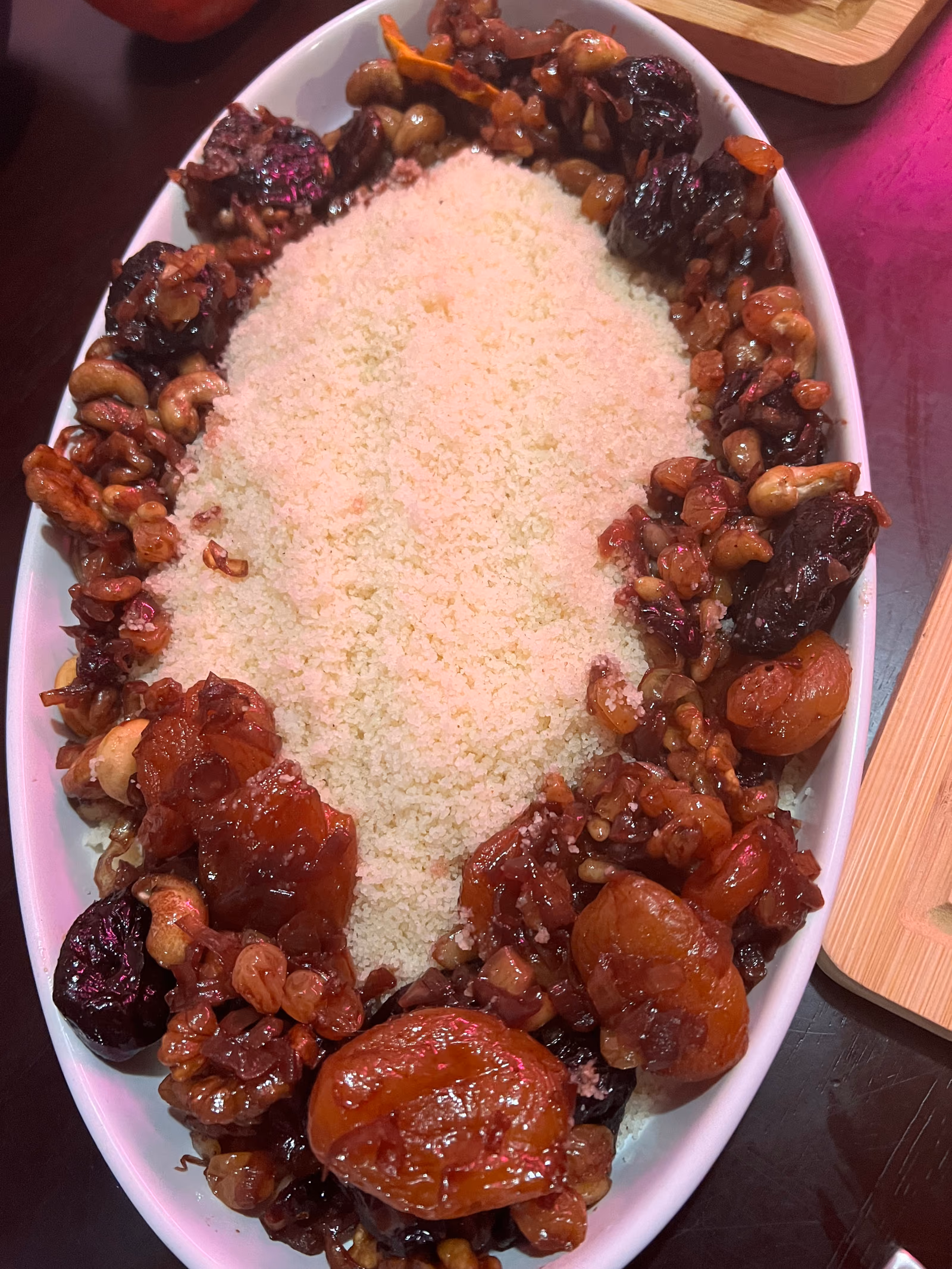 A platter of pale couscous ringed by a dark red meat and tomato stew.