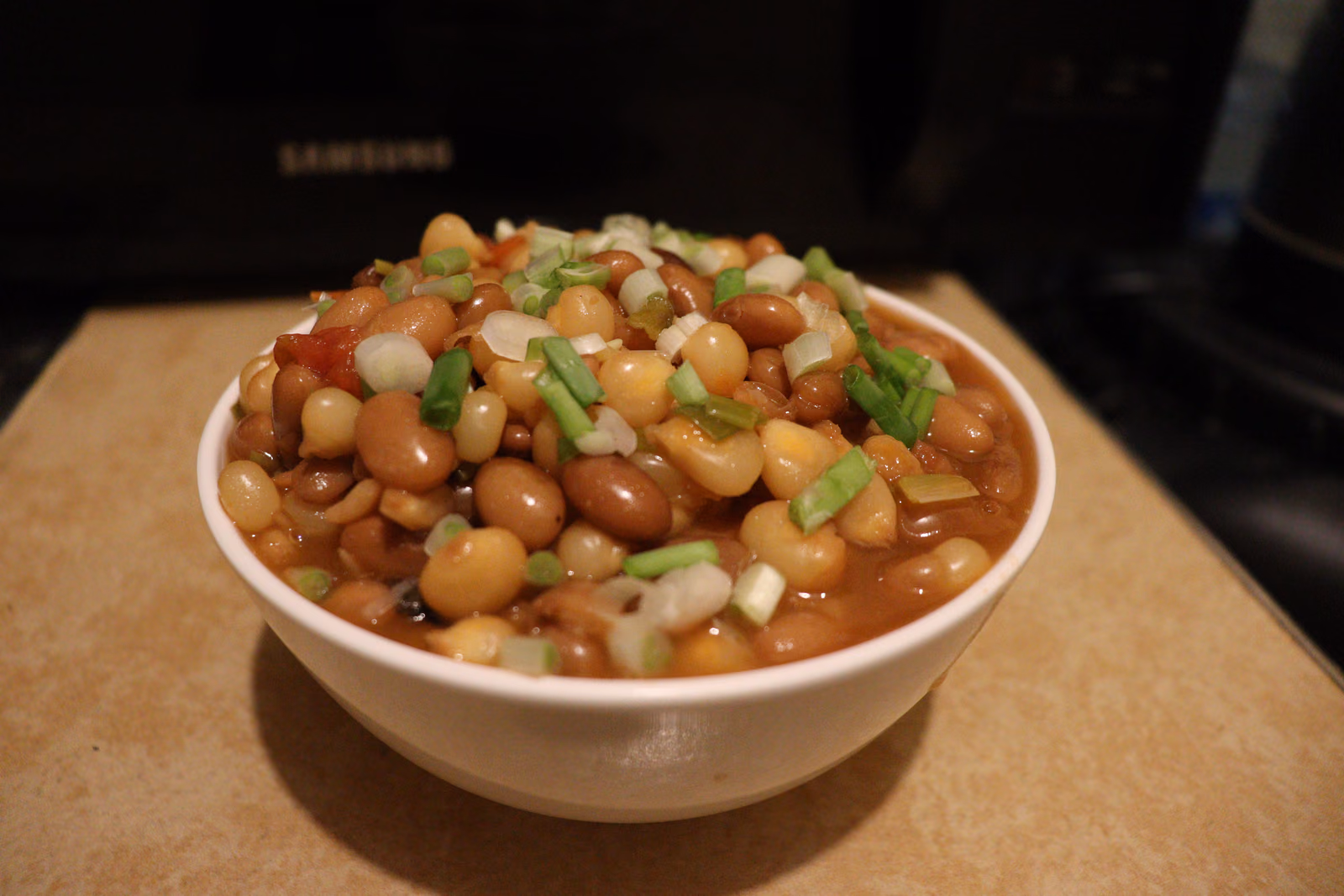 A bowl of githeri: boiled maize kernels and beans in a light broth, topped with herbs.
