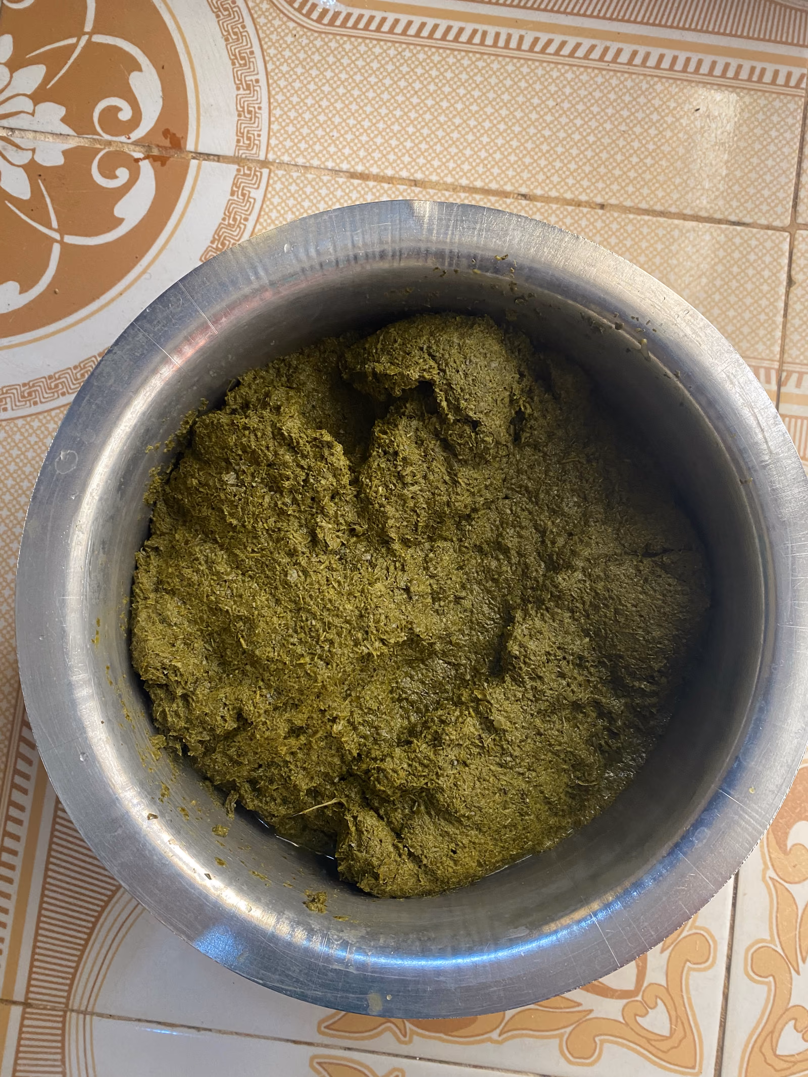 A wide metal pot of dark green cooked leafy relish.