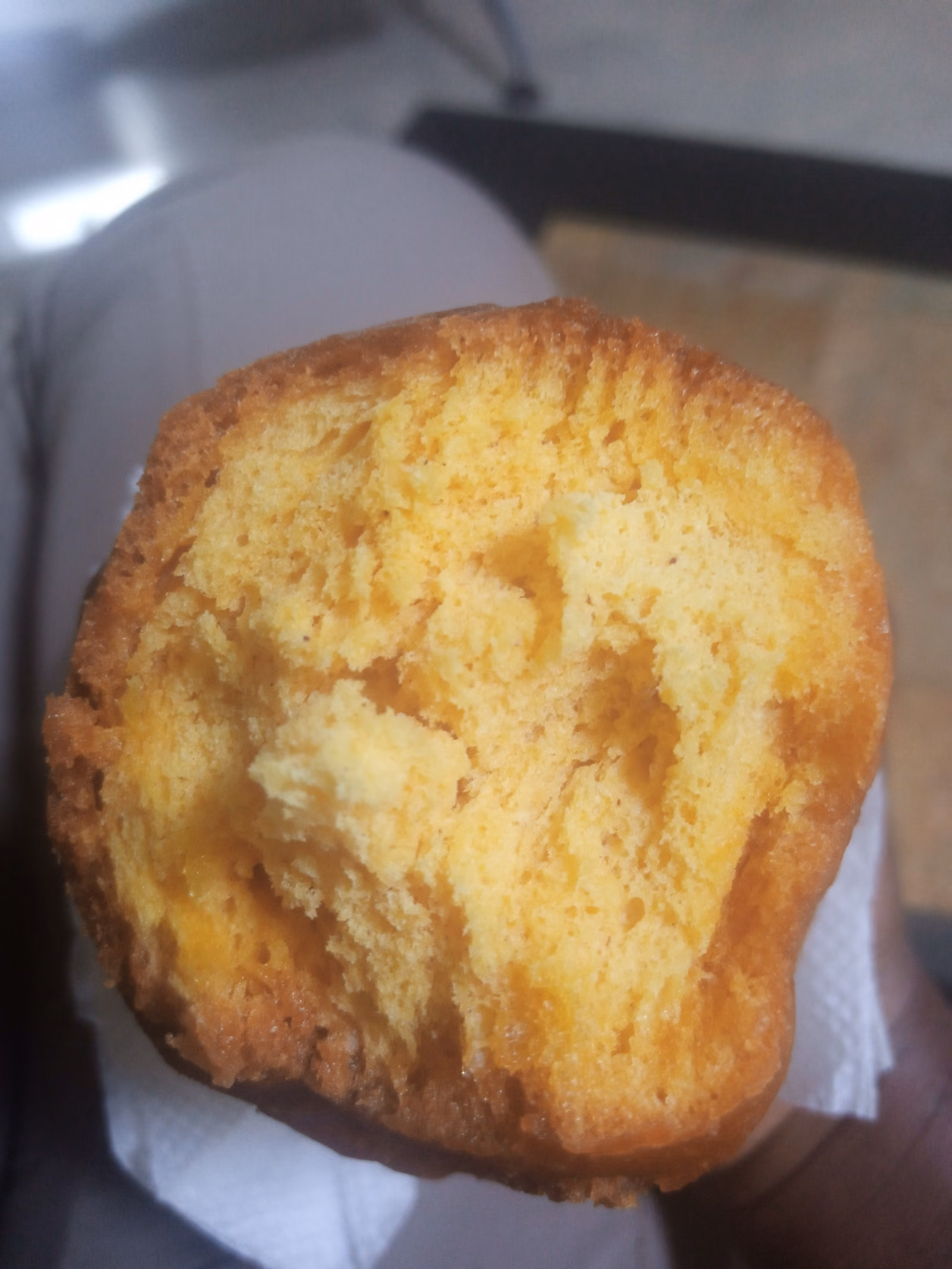 Golden deep-fried mandazi dough, split to show the soft crumb inside.