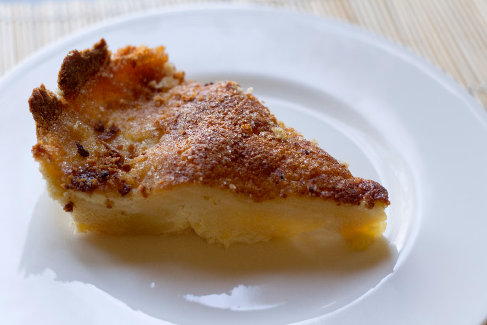 A slice of melktert, its pale set custard filling dusted with cinnamon.