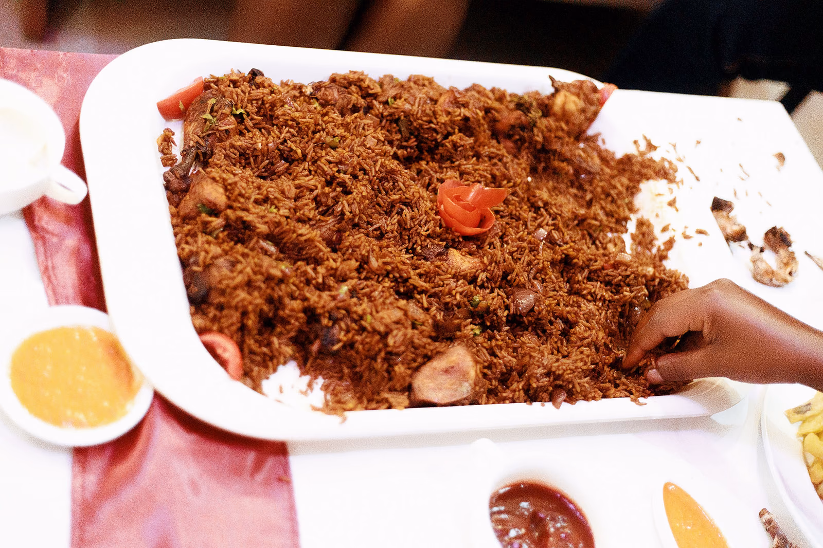 A wide dish of spiced brown rice studded with pieces of meat, served for a crowd.